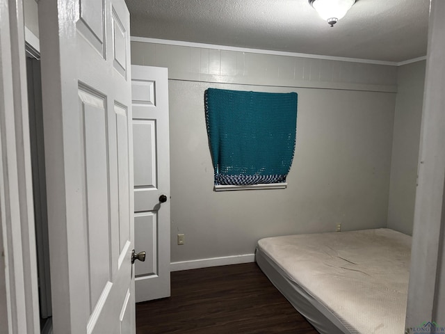 bedroom featuring dark wood-style floors, crown molding, a textured ceiling, and baseboards