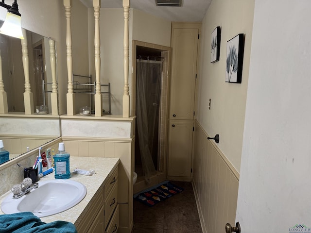 full bathroom with a stall shower, a wainscoted wall, and vanity