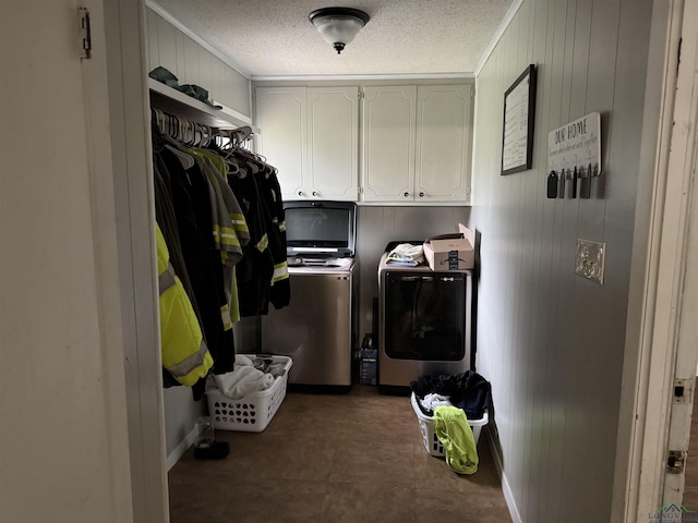 clothes washing area featuring cabinet space, a textured ceiling, and washing machine and clothes dryer