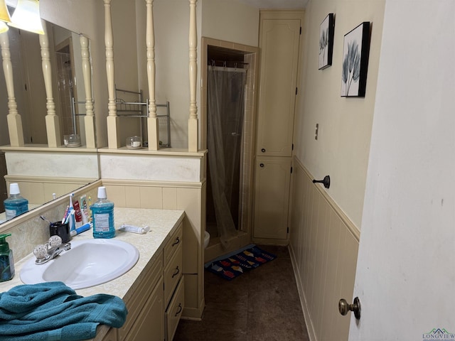 bathroom featuring wainscoting, a shower stall, and vanity