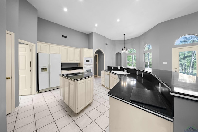 1804 W Lake Dr, Gladewater, TX 75647 - kitchen with a towering ceiling, white appliances, light tile patterned floors, cream cabinetry, and a kitchen island