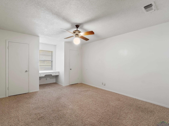 unfurnished bedroom with ceiling fan, carpet, and a textured ceiling