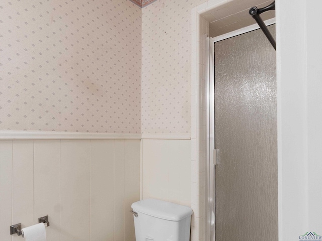 bathroom featuring toilet and a shower with shower door