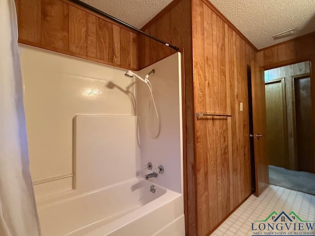 bathroom featuring a textured ceiling, shower / bath combination, and wooden walls