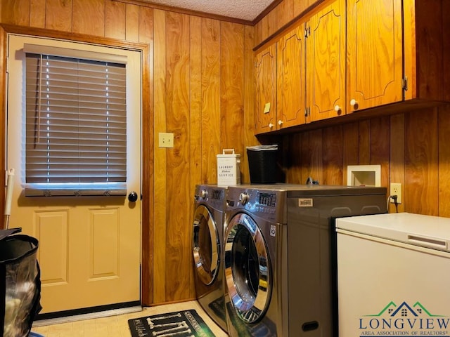 clothes washing area featuring wood walls, cabinets, and washing machine and dryer