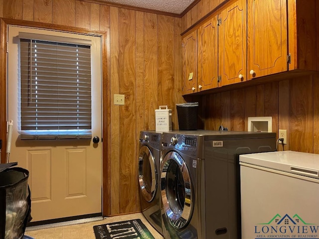 laundry area featuring wood walls, cabinets, and separate washer and dryer