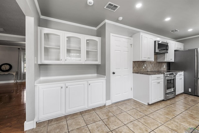 kitchen featuring ornamental molding, stainless steel appliances, visible vents, and glass insert cabinets