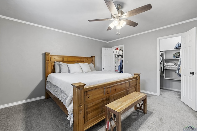 carpeted bedroom with ceiling fan, baseboards, a walk in closet, and crown molding