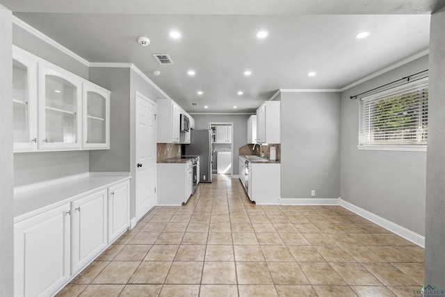 kitchen featuring crown molding, tasteful backsplash, white cabinets, washer / clothes dryer, and visible vents