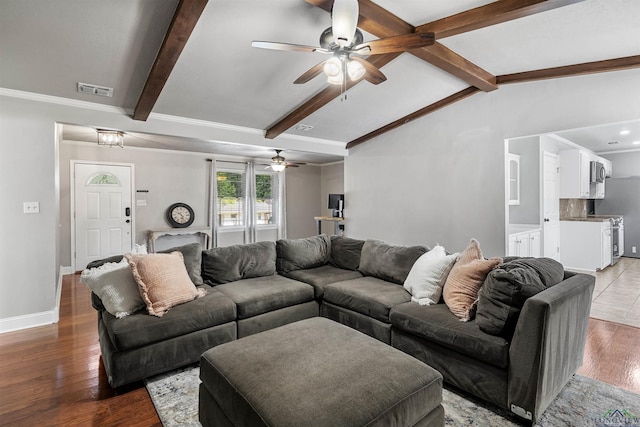 living area featuring wood finished floors, vaulted ceiling with beams, ceiling fan, baseboards, and visible vents