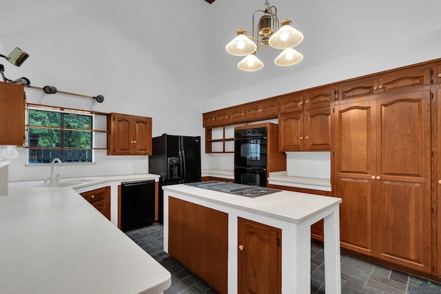 kitchen featuring sink, black appliances, pendant lighting, an inviting chandelier, and a high ceiling