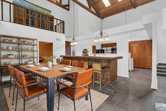 dining area with high vaulted ceiling, a skylight, beam ceiling, wood ceiling, and a chandelier