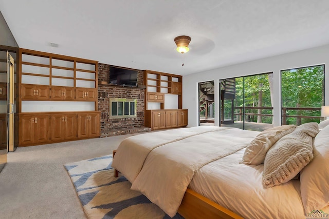 bedroom with access to exterior, ceiling fan, light colored carpet, and a brick fireplace