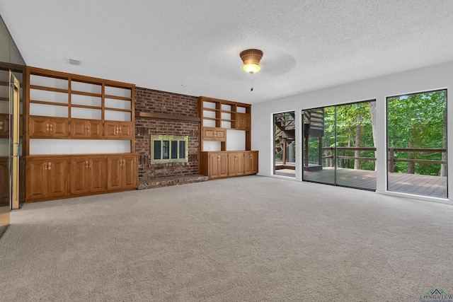 unfurnished living room with light carpet, a textured ceiling, a brick fireplace, and ceiling fan