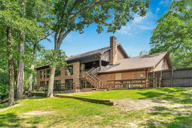 rear view of property featuring stairway, a deck, a lawn, and brick siding