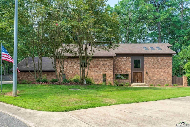 view of front of home with brick siding, a front yard, and fence