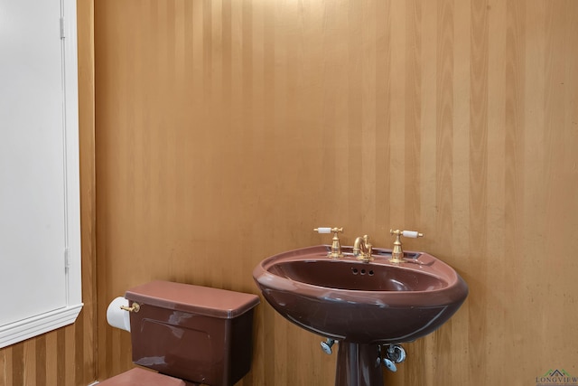 bathroom with wooden walls, sink, and toilet