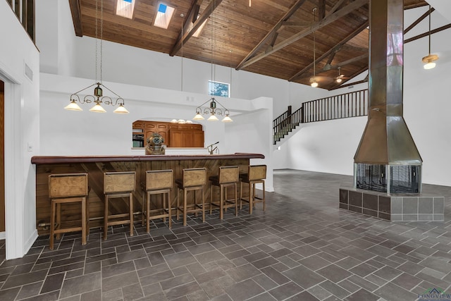 kitchen with wood ceiling, a breakfast bar, beam ceiling, decorative light fixtures, and high vaulted ceiling