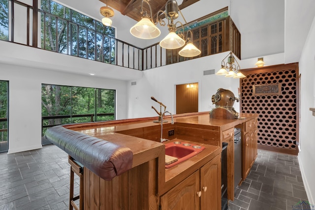 kitchen featuring a towering ceiling, sink, beamed ceiling, dishwasher, and hanging light fixtures