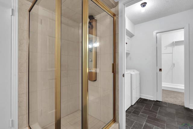 bathroom with washer and dryer, an enclosed shower, and a textured ceiling