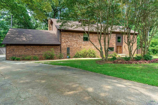 view of home's exterior with brick siding, a shingled roof, a chimney, and a yard