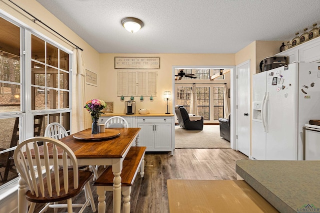 dining space with ceiling fan, a textured ceiling, and wood finished floors