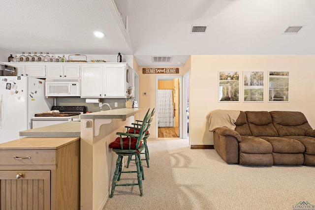 kitchen with open floor plan, visible vents, range, and white microwave