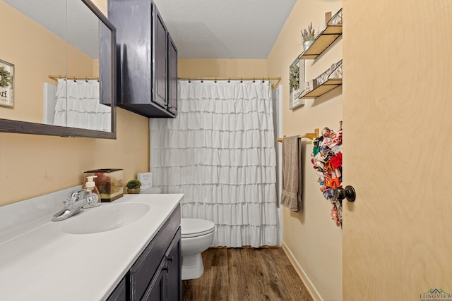 bathroom with toilet, a textured ceiling, vanity, wood finished floors, and a shower with curtain