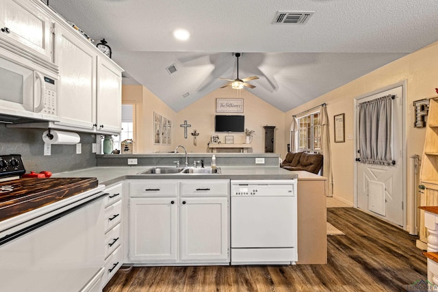 kitchen with dark wood finished floors, visible vents, a sink, white appliances, and a peninsula