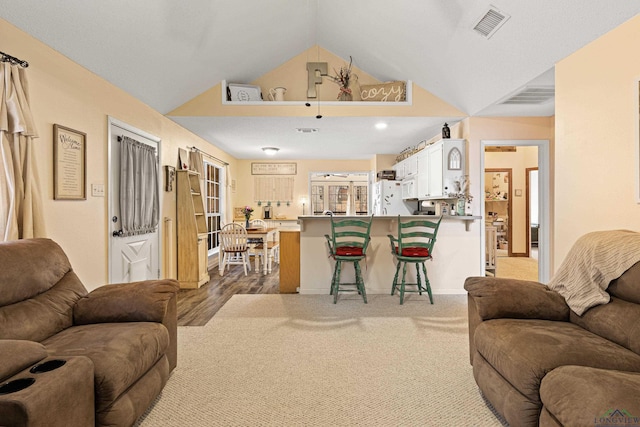 carpeted living room featuring lofted ceiling and visible vents