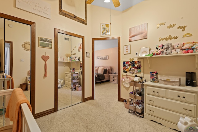 hall featuring a high ceiling, light colored carpet, and baseboards