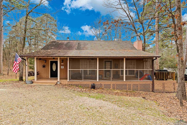 rear view of property featuring a chimney and a sunroom