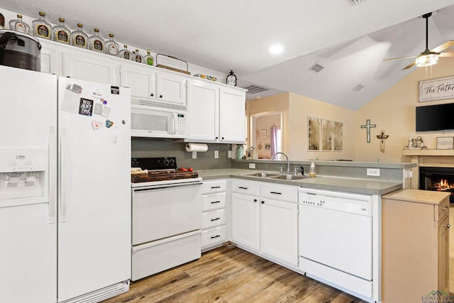 kitchen featuring white appliances, visible vents, a peninsula, white cabinetry, and a sink