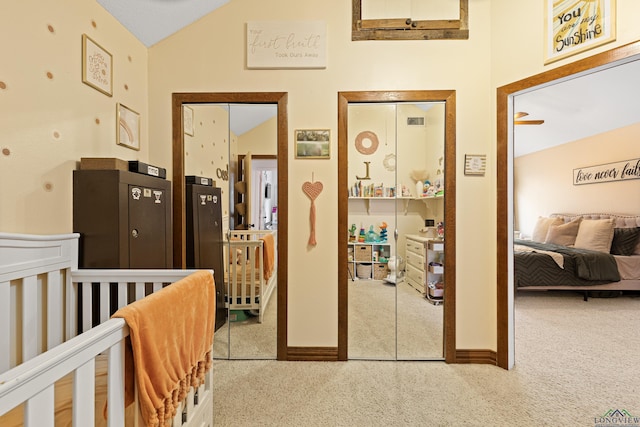 corridor featuring lofted ceiling, carpet, visible vents, and baseboards