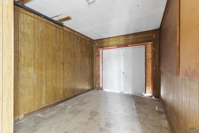 interior space featuring a textured ceiling and wooden walls