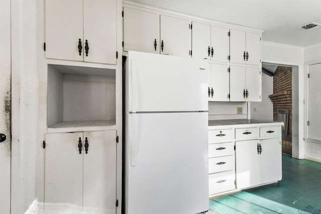 kitchen with a brick fireplace, white cabinets, a textured ceiling, and white refrigerator