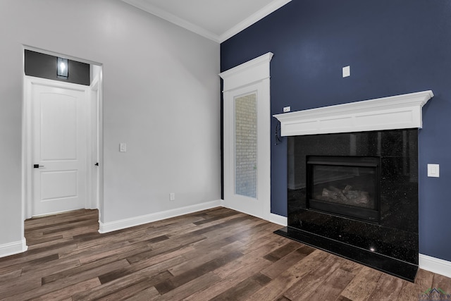 unfurnished living room featuring baseboards, crown molding, a glass covered fireplace, and dark wood-type flooring