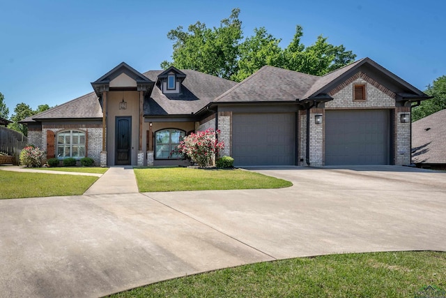 view of front facade with brick siding, an attached garage, driveway, and a front yard