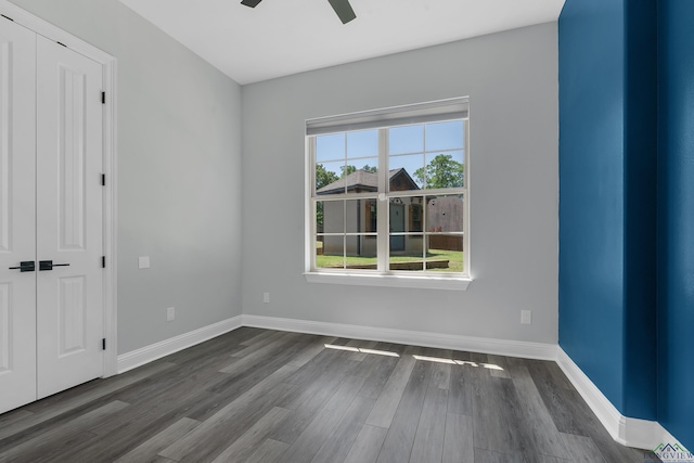 unfurnished bedroom featuring baseboards, a ceiling fan, dark wood-type flooring, and a closet