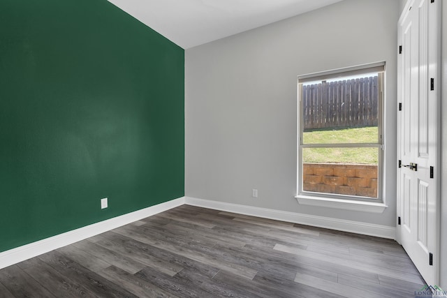 spare room featuring dark wood-type flooring and baseboards