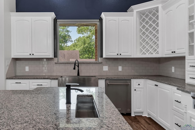 kitchen with decorative backsplash, white cabinetry, dark stone countertops, and a sink
