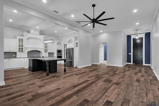 kitchen with stainless steel appliances, a center island with sink, visible vents, a ceiling fan, and ornamental molding