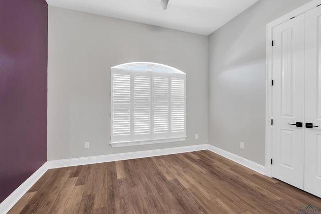 empty room featuring baseboards, wood finished floors, and ceiling fan