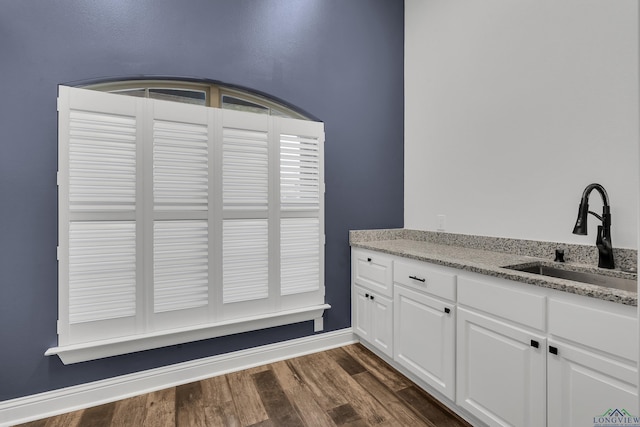 interior space with dark wood finished floors, baseboards, and a sink
