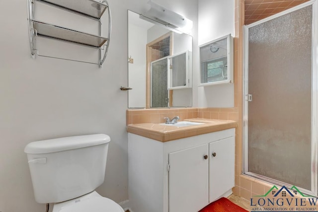 bathroom featuring a shower with door, vanity, and toilet