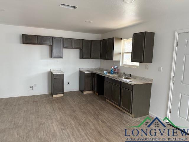 kitchen featuring light countertops, a sink, visible vents, and light wood finished floors