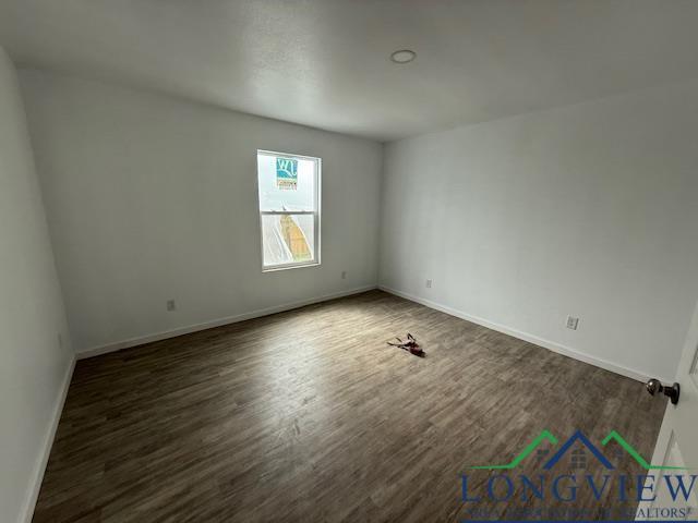 spare room with dark wood-style floors and baseboards