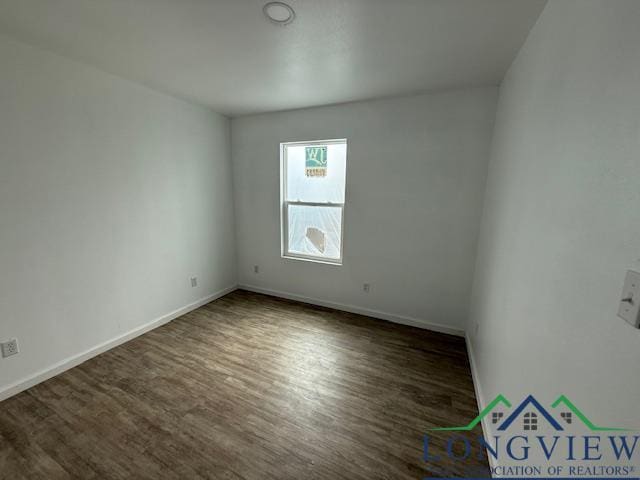 spare room featuring dark wood-style flooring and baseboards