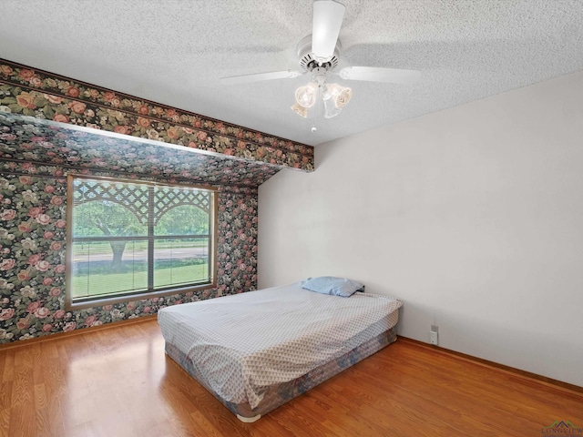 bedroom with wood-type flooring, a textured ceiling, and ceiling fan