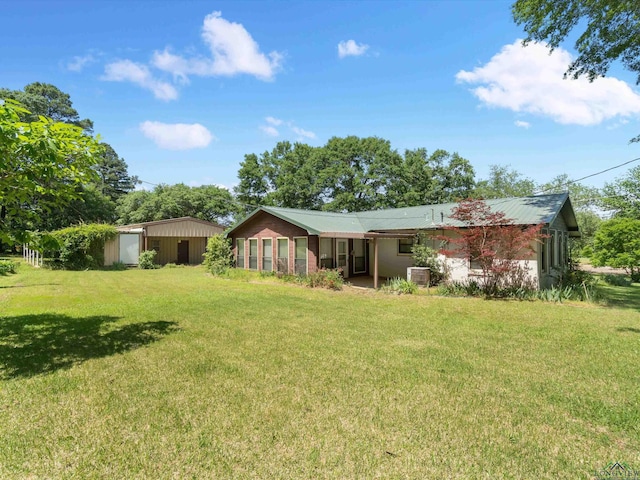 rear view of house featuring central AC unit, an outdoor structure, and a lawn